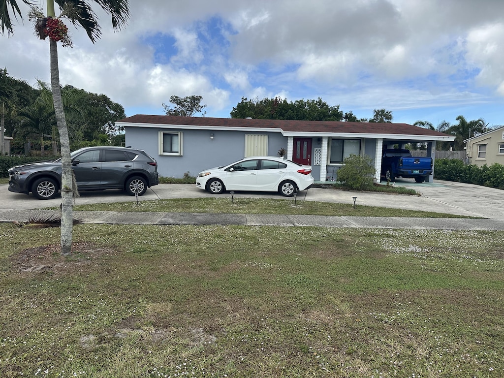 view of front of property featuring a front yard and a carport