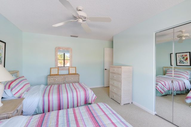 bedroom featuring a textured ceiling, ceiling fan, light carpet, and a closet