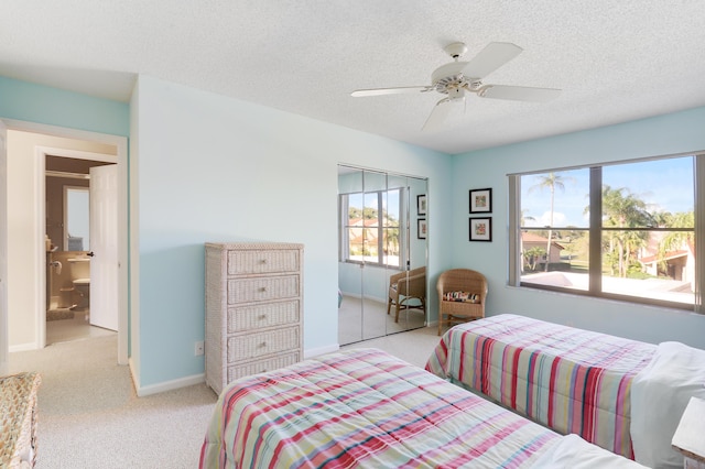 bedroom featuring multiple windows, ceiling fan, a closet, and light colored carpet