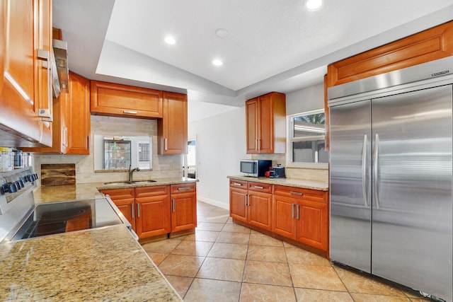 kitchen featuring lofted ceiling, backsplash, sink, light tile patterned floors, and appliances with stainless steel finishes