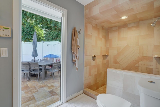 bathroom with a tile shower and toilet