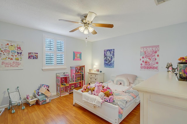 bedroom with ceiling fan, light hardwood / wood-style flooring, and a textured ceiling