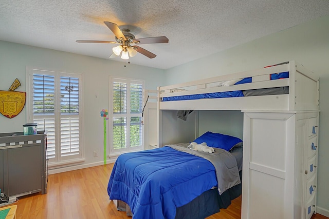 bedroom with a textured ceiling, hardwood / wood-style flooring, and ceiling fan