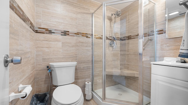 bathroom featuring tile walls, vanity, an enclosed shower, and toilet