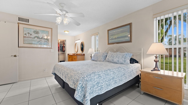 tiled bedroom featuring ceiling fan, a spacious closet, and a closet