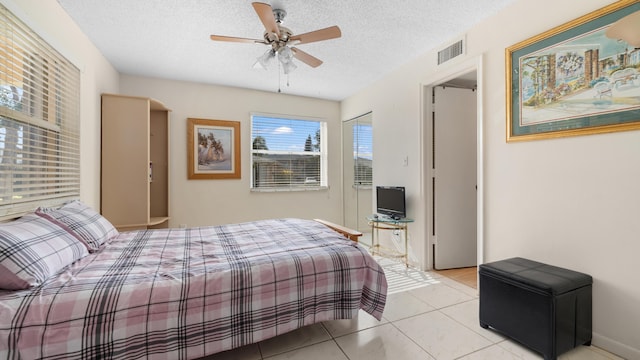 tiled bedroom with a textured ceiling and ceiling fan