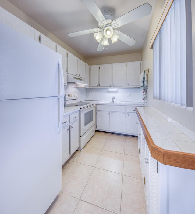 kitchen with white appliances, ceiling fan, tile countertops, white cabinets, and light tile patterned flooring