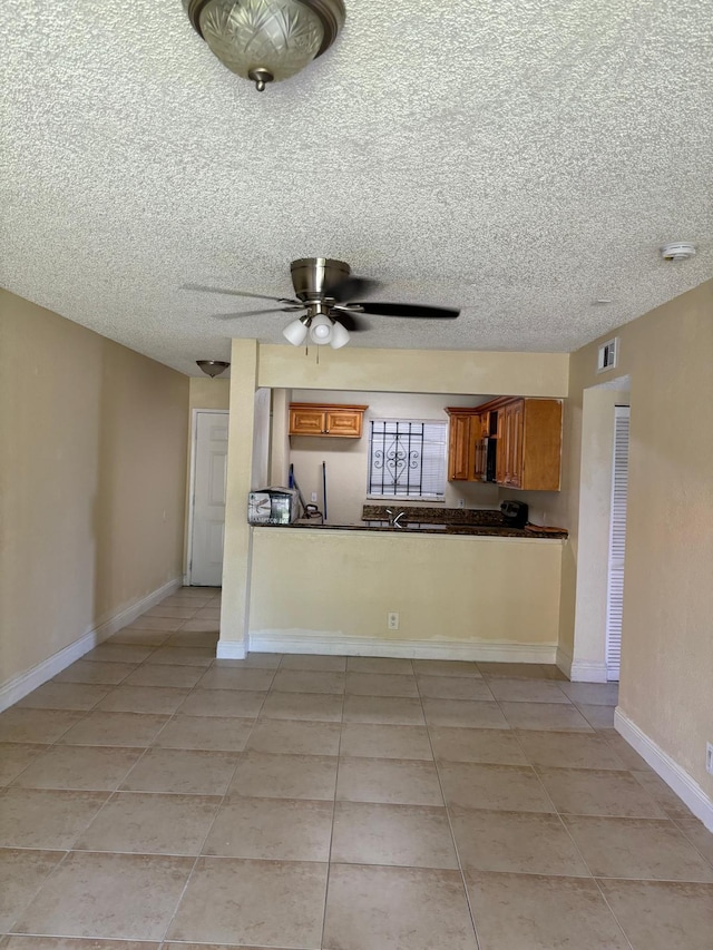 kitchen with kitchen peninsula, light tile patterned floors, a textured ceiling, and ceiling fan