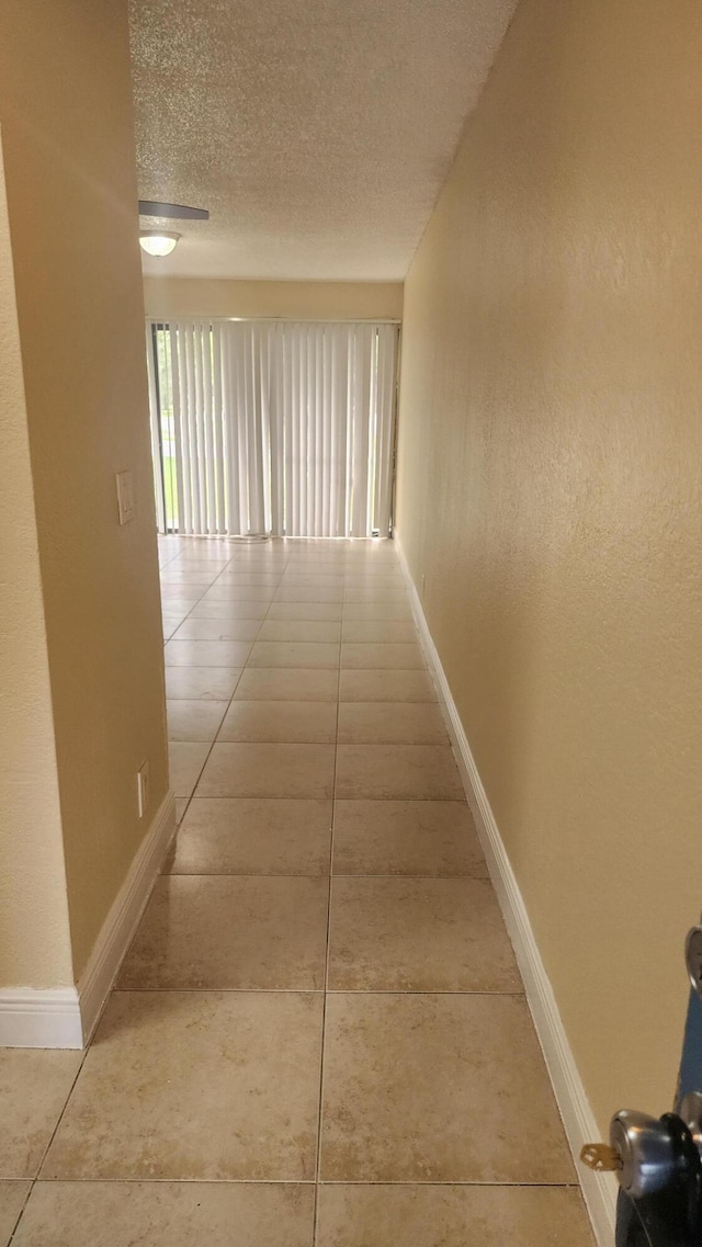 hall with tile patterned floors and a textured ceiling