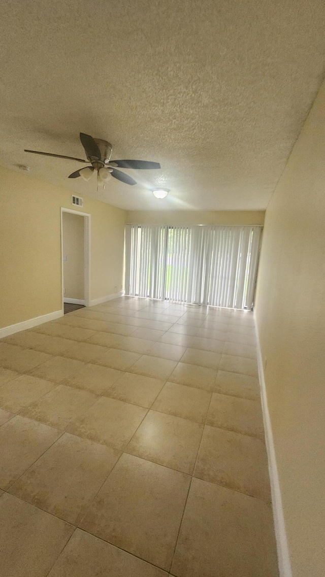 tiled spare room featuring a textured ceiling and ceiling fan