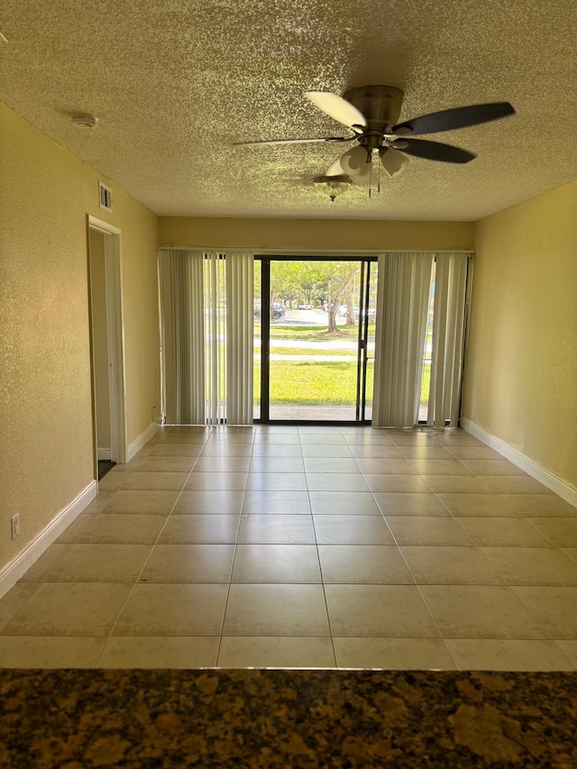 tiled empty room with ceiling fan and a textured ceiling