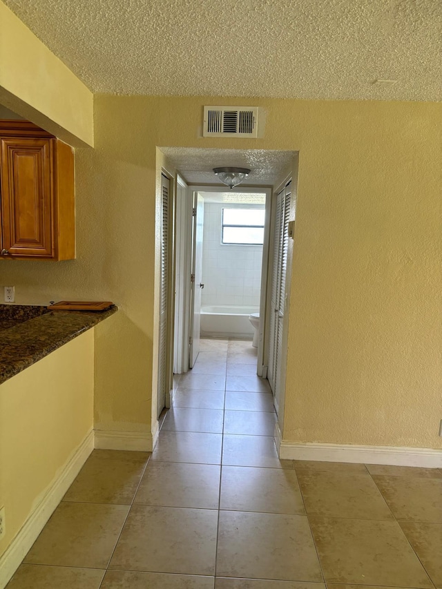 hallway featuring light tile patterned floors and a textured ceiling