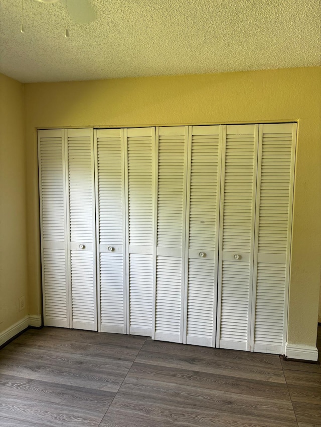 unfurnished bedroom featuring a textured ceiling, a closet, and dark wood-type flooring