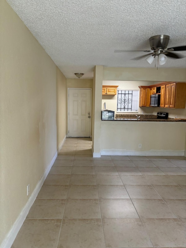 kitchen with kitchen peninsula, a textured ceiling, ceiling fan, and light tile patterned flooring