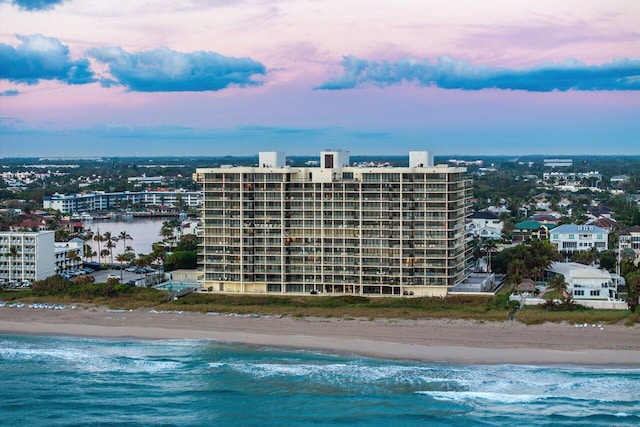 aerial view at dusk featuring a beach view and a water view