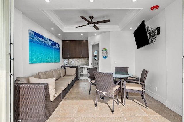 dining area with ceiling fan, beverage cooler, ornamental molding, and a tray ceiling