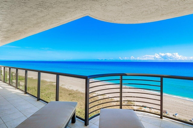 balcony featuring a beach view and a water view