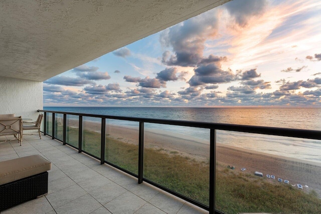 balcony at dusk with a beach view and a water view