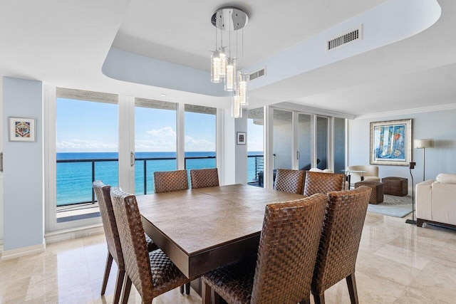 dining area featuring a chandelier, floor to ceiling windows, and a water view