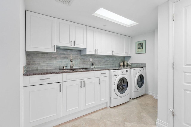 laundry area featuring sink, cabinets, light tile patterned floors, washer and clothes dryer, and a skylight