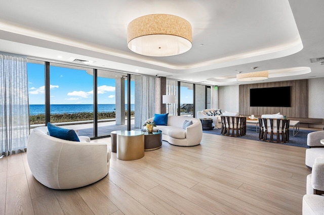 interior space with a raised ceiling, light wood-type flooring, and floor to ceiling windows