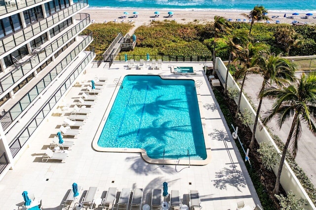 view of pool with a patio area, a view of the beach, and a water view