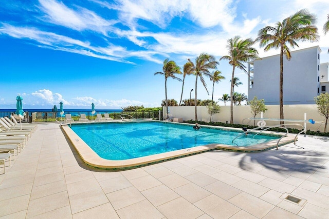 view of pool featuring a patio and a water view