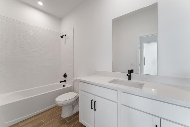 full bathroom featuring toilet, vanity, wood-type flooring, and tiled shower / bath