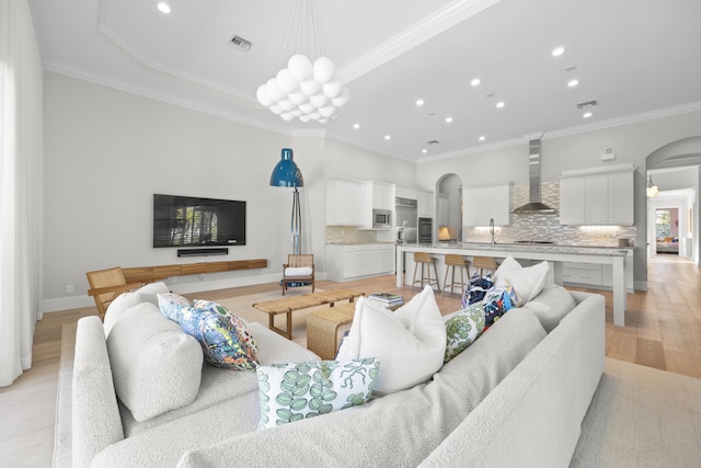 living room featuring light hardwood / wood-style floors, crown molding, and sink