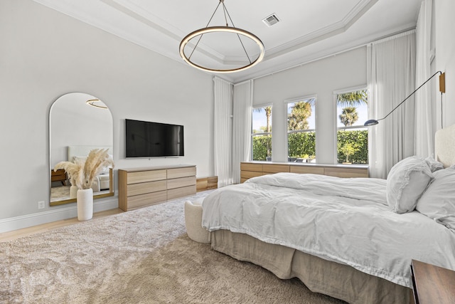 bedroom featuring hardwood / wood-style flooring, a raised ceiling, and crown molding