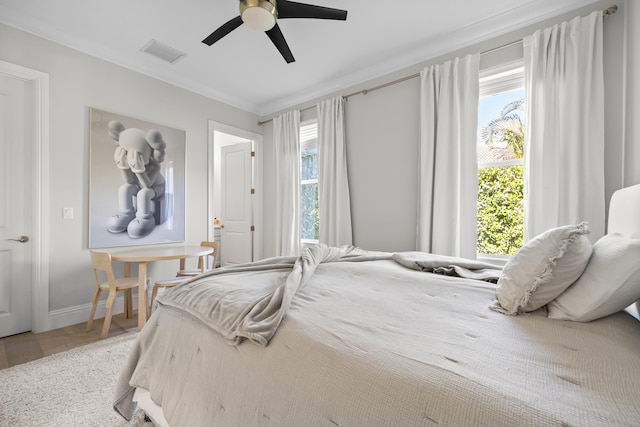 bedroom featuring multiple windows, ceiling fan, hardwood / wood-style floors, and ornamental molding