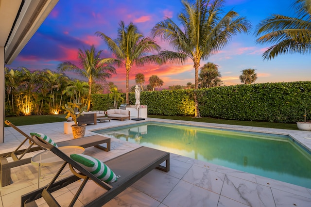 pool at dusk with an outdoor living space and a patio