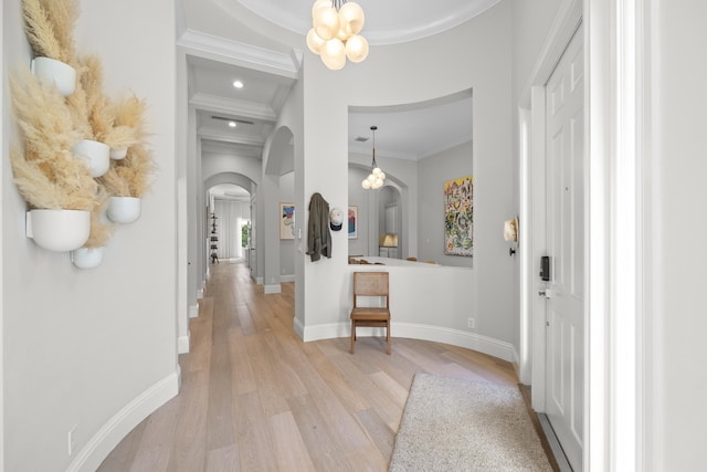 hall with beam ceiling, light wood-type flooring, an inviting chandelier, and ornamental molding