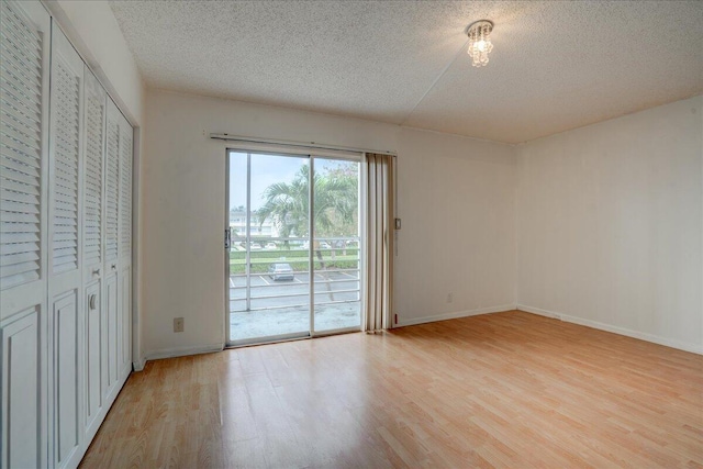 interior space with access to exterior, light wood-type flooring, a textured ceiling, and a closet