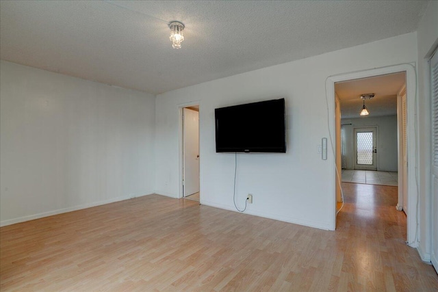 unfurnished room with a textured ceiling and light hardwood / wood-style flooring