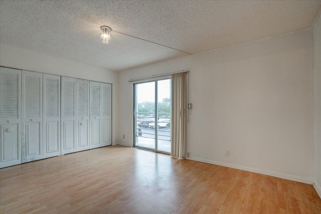 unfurnished bedroom with light wood-type flooring, a textured ceiling, and access to outside