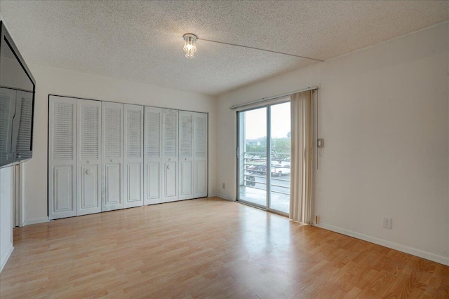 unfurnished bedroom featuring access to exterior, light hardwood / wood-style flooring, and a textured ceiling