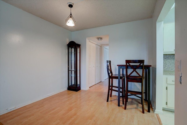 dining area with a textured ceiling and light hardwood / wood-style floors