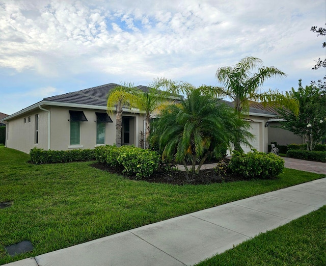 view of front of property featuring a garage, decorative driveway, a front yard, and stucco siding