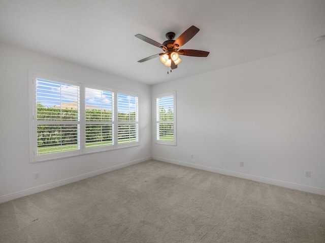 spare room featuring light carpet, ceiling fan, and baseboards