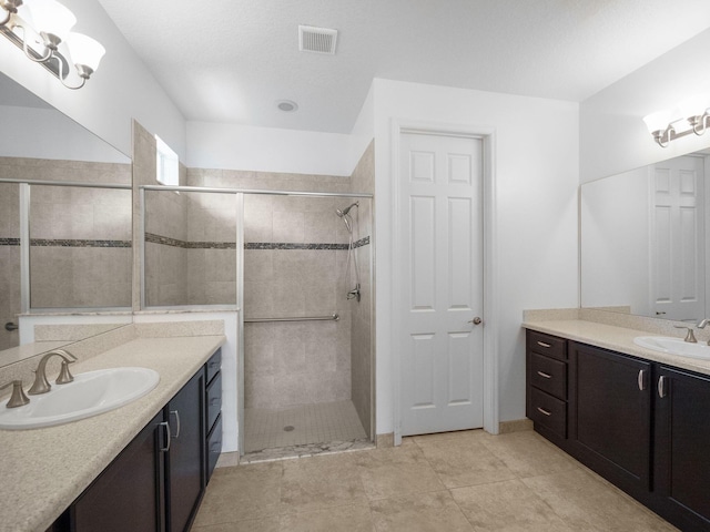 bathroom featuring tile patterned flooring, a textured ceiling, vanity, and an enclosed shower