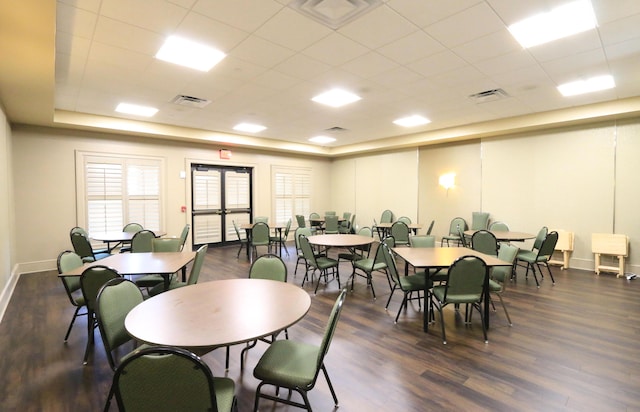 dining room with dark hardwood / wood-style flooring and a drop ceiling