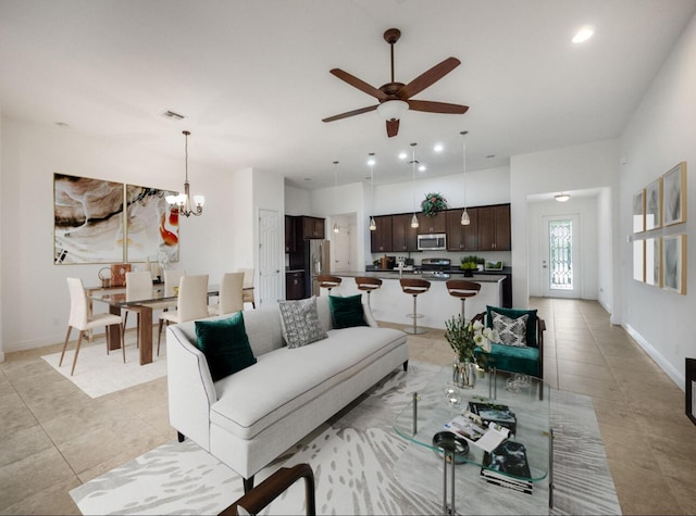 living room featuring ceiling fan with notable chandelier, visible vents, baseboards, and light tile patterned floors