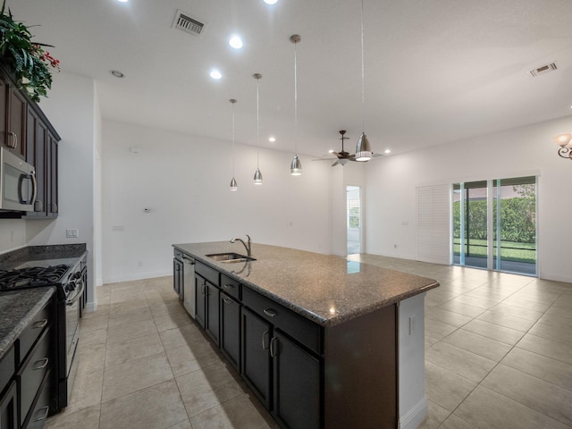 kitchen featuring black range with gas stovetop, a kitchen island with sink, ceiling fan, sink, and hanging light fixtures