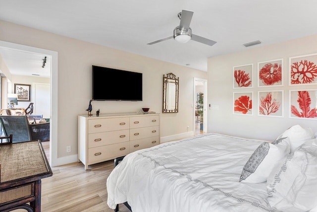 bedroom with a ceiling fan, baseboards, visible vents, and light wood finished floors