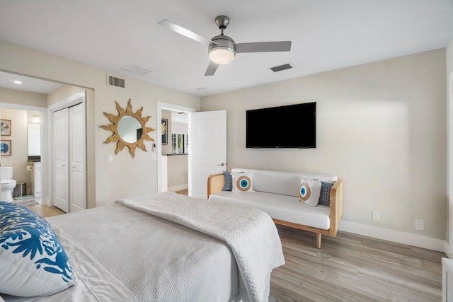 bedroom featuring baseboards, ensuite bath, visible vents, and light wood-style floors