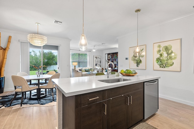 kitchen with dark brown cabinetry, ceiling fan, sink, crown molding, and a center island with sink