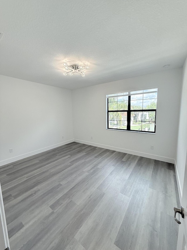 spare room featuring wood-type flooring and a textured ceiling