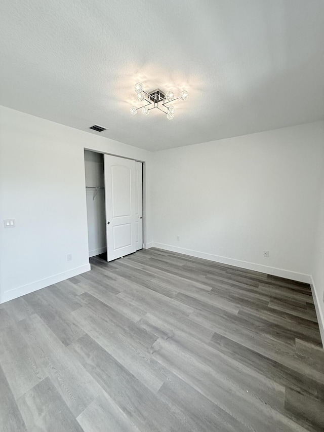 unfurnished bedroom with a textured ceiling, light wood-type flooring, and a closet