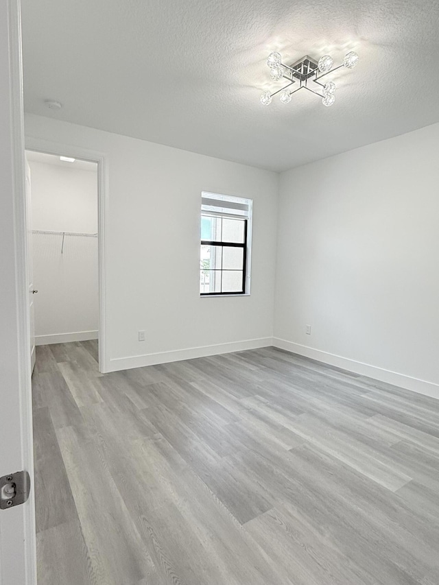 unfurnished room with light hardwood / wood-style floors and a textured ceiling